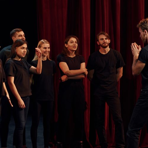 Group of actors in dark colored clothes on rehearsal in the theater.